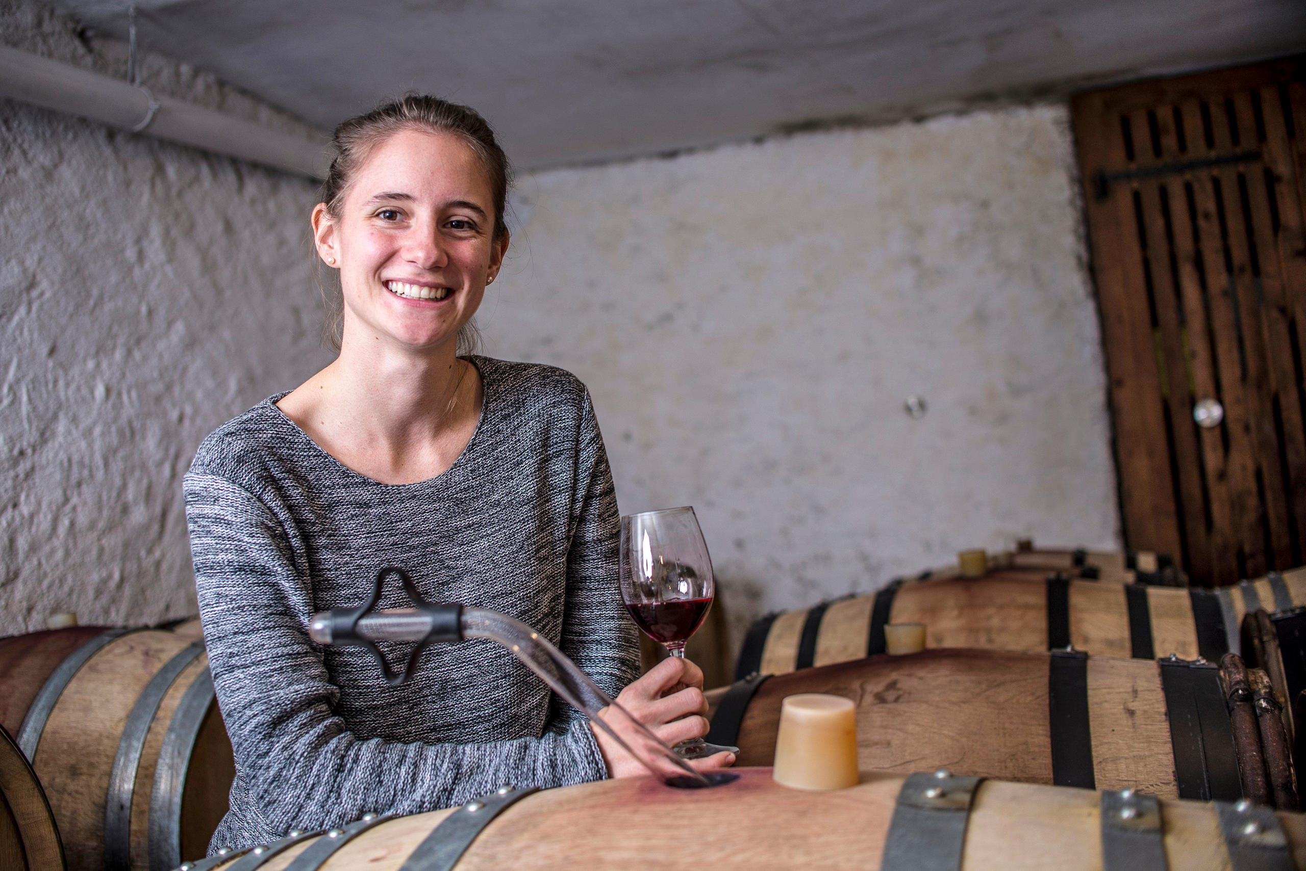 donna con un calice di vino tra delle botti