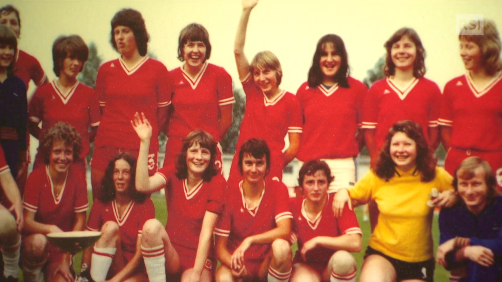 Squadra di calcio femminile con casacca rossa in foto di gruppo nella tipica posizione delle squadre di calcio