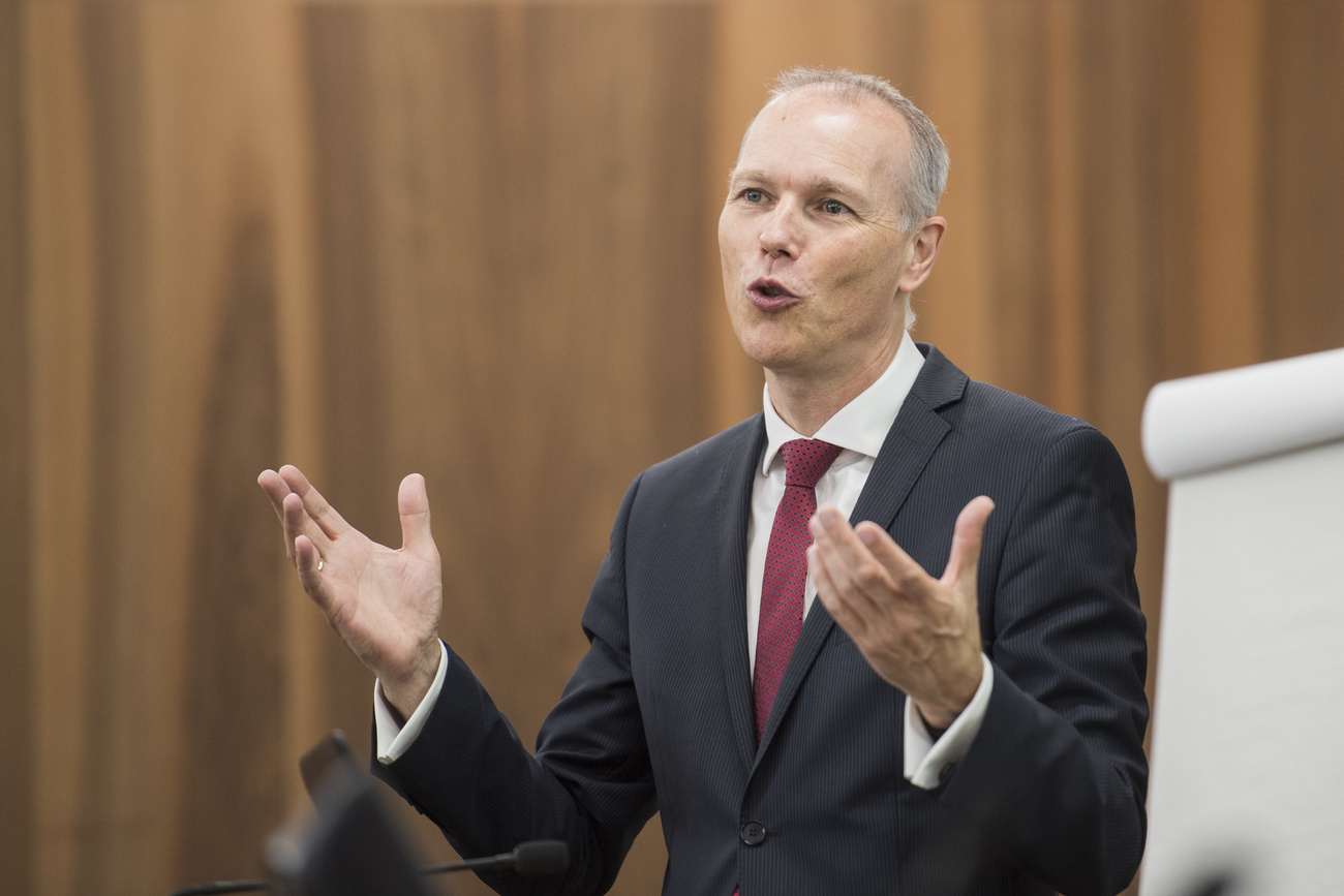 Man in suit speaking next to a flip chart