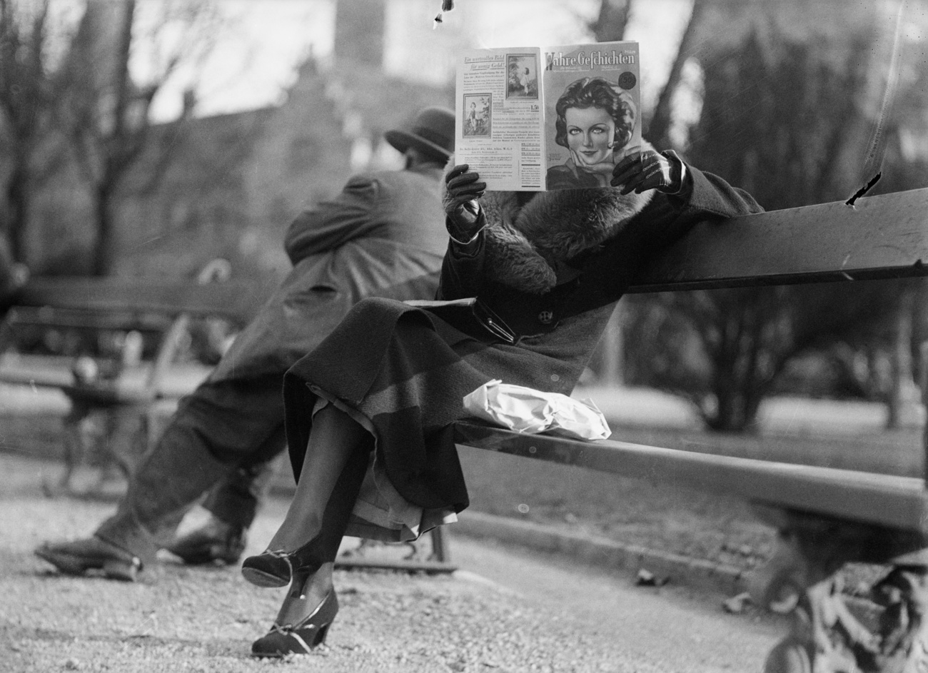 Une femme lit un journal sur un banc