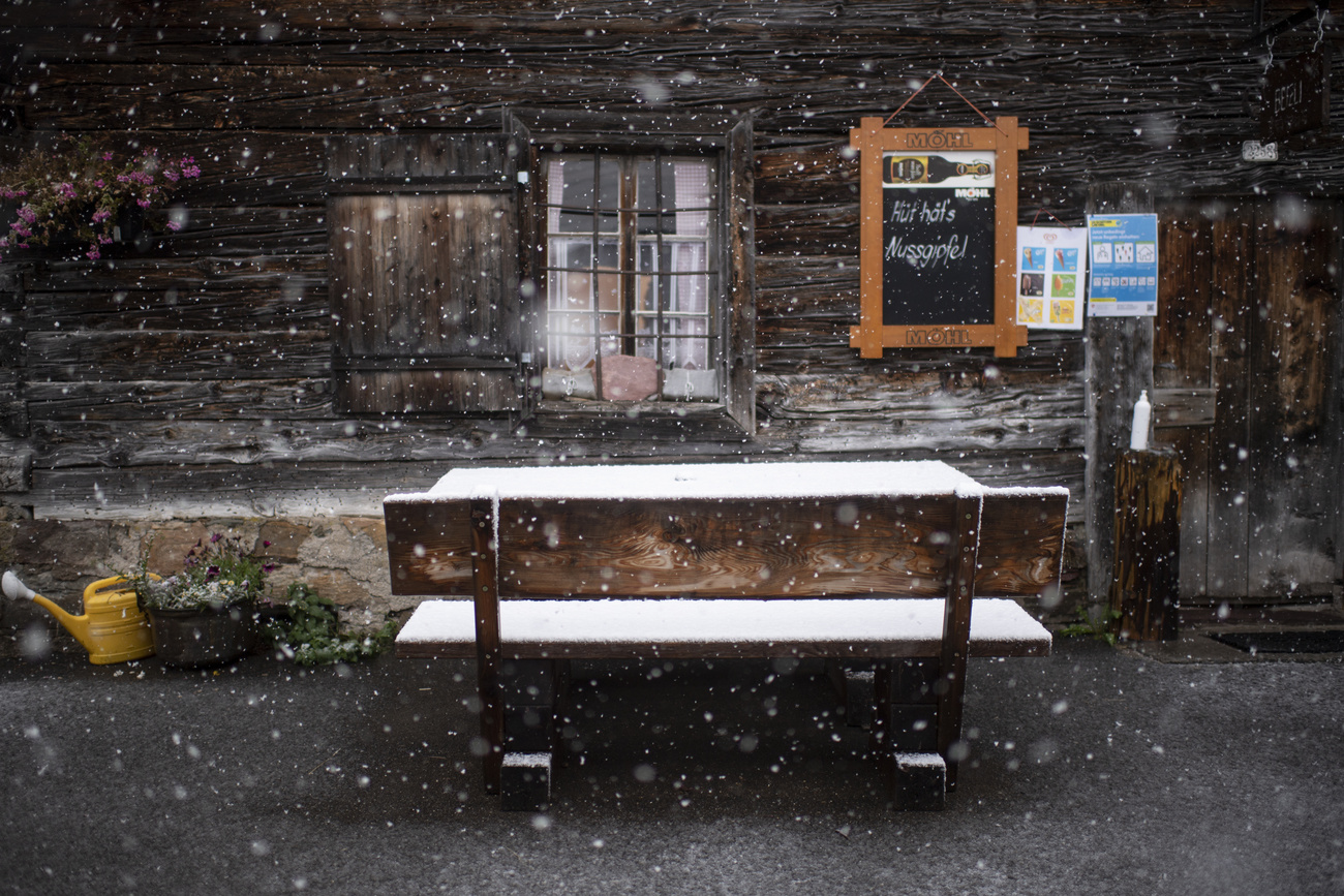 Bench and table of a mountain restaurant covered in snow