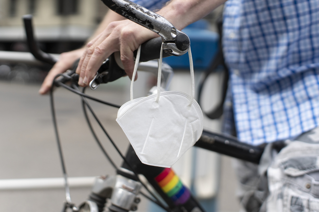 Uomo in bicicletta con una mascherina fissato al manubrio della bici.