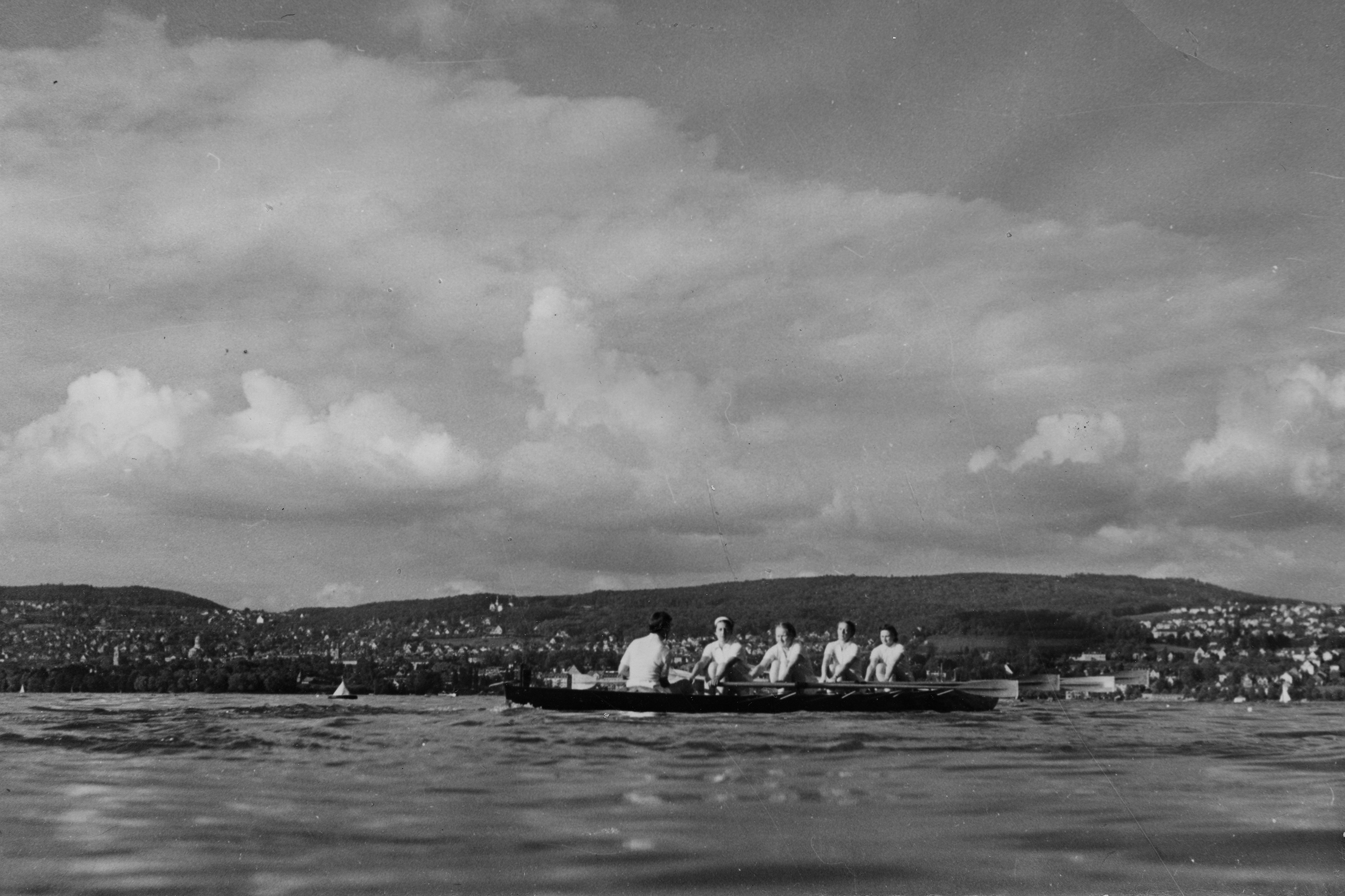 Women row on a lake.