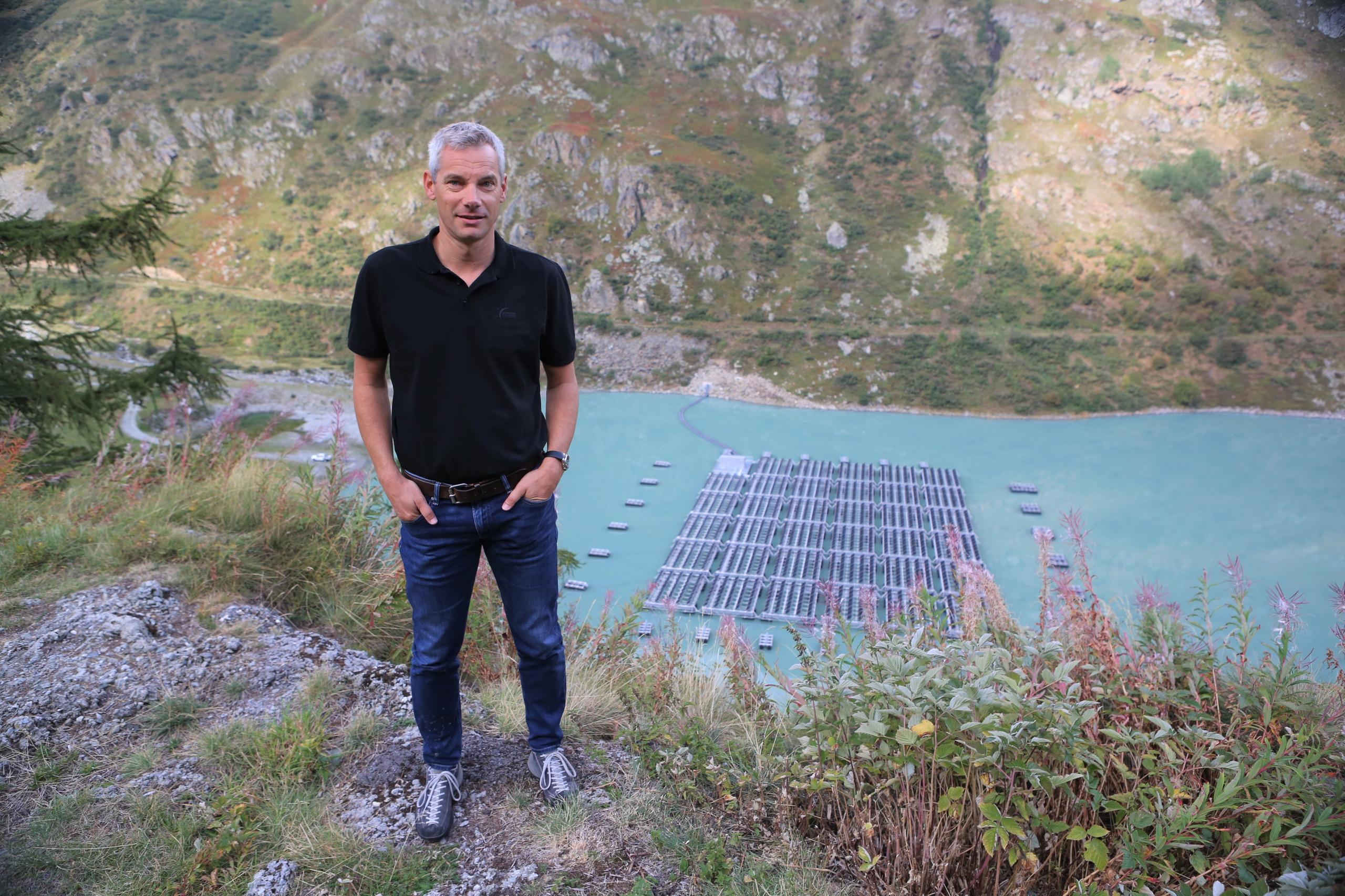 A man standing in front of floating solar panels on the Lac des Toules reservoir