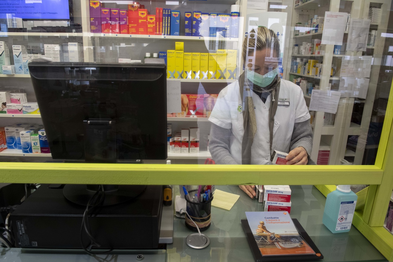 donna con mascherina al banco di una farmacia