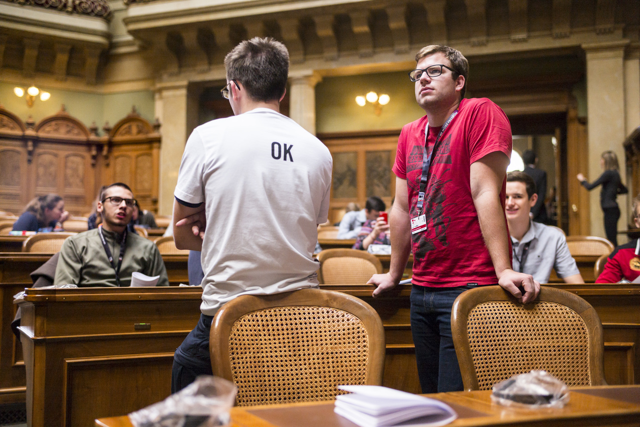 Jugendliche, die in der Schweizerischen Volkskammer (Nationalrat) sitzen und miteinander im Gespräch sind