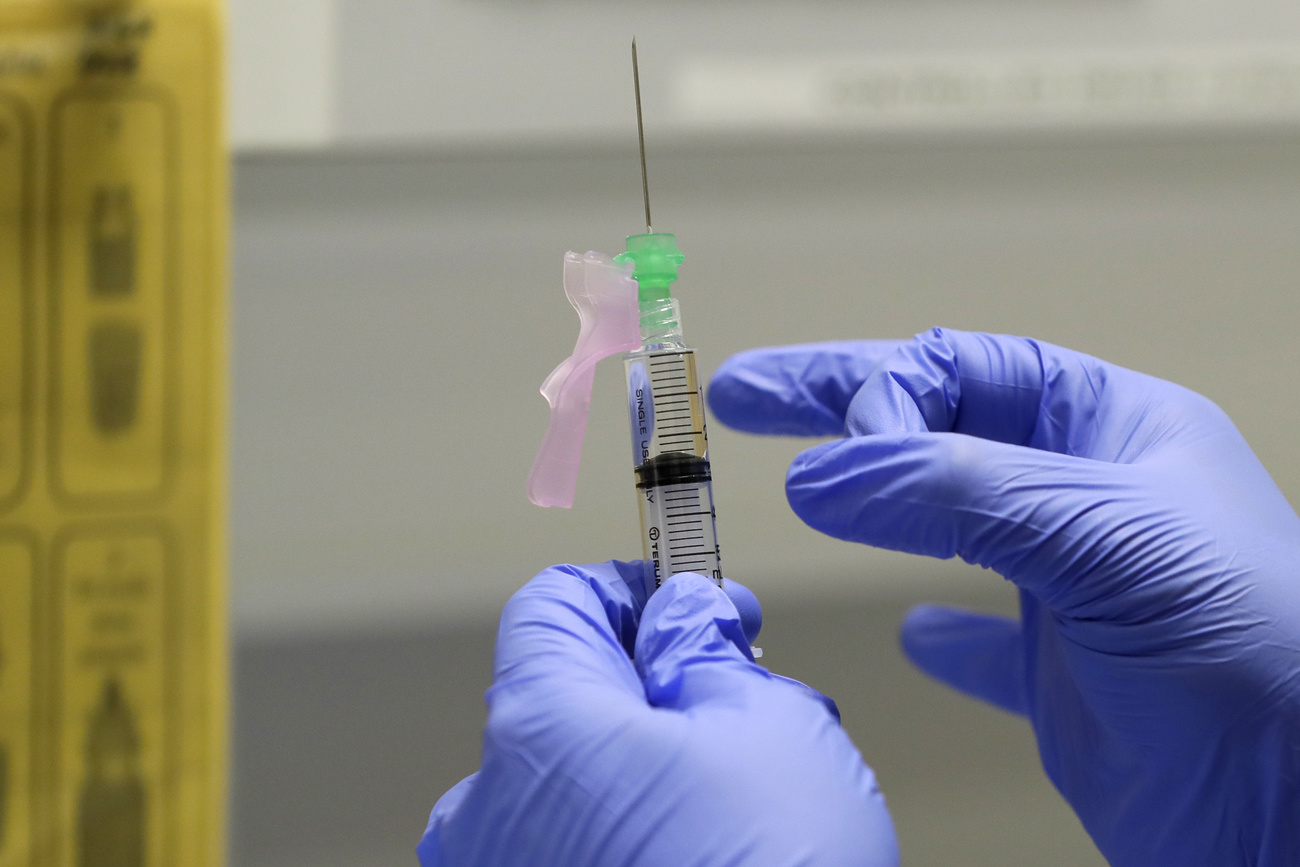 gloved hands prepping a syringe