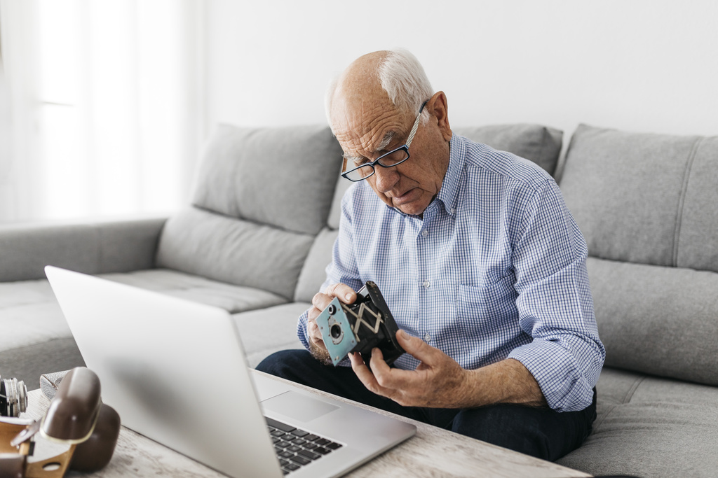 Un señor mayor con una cámara y una computadora