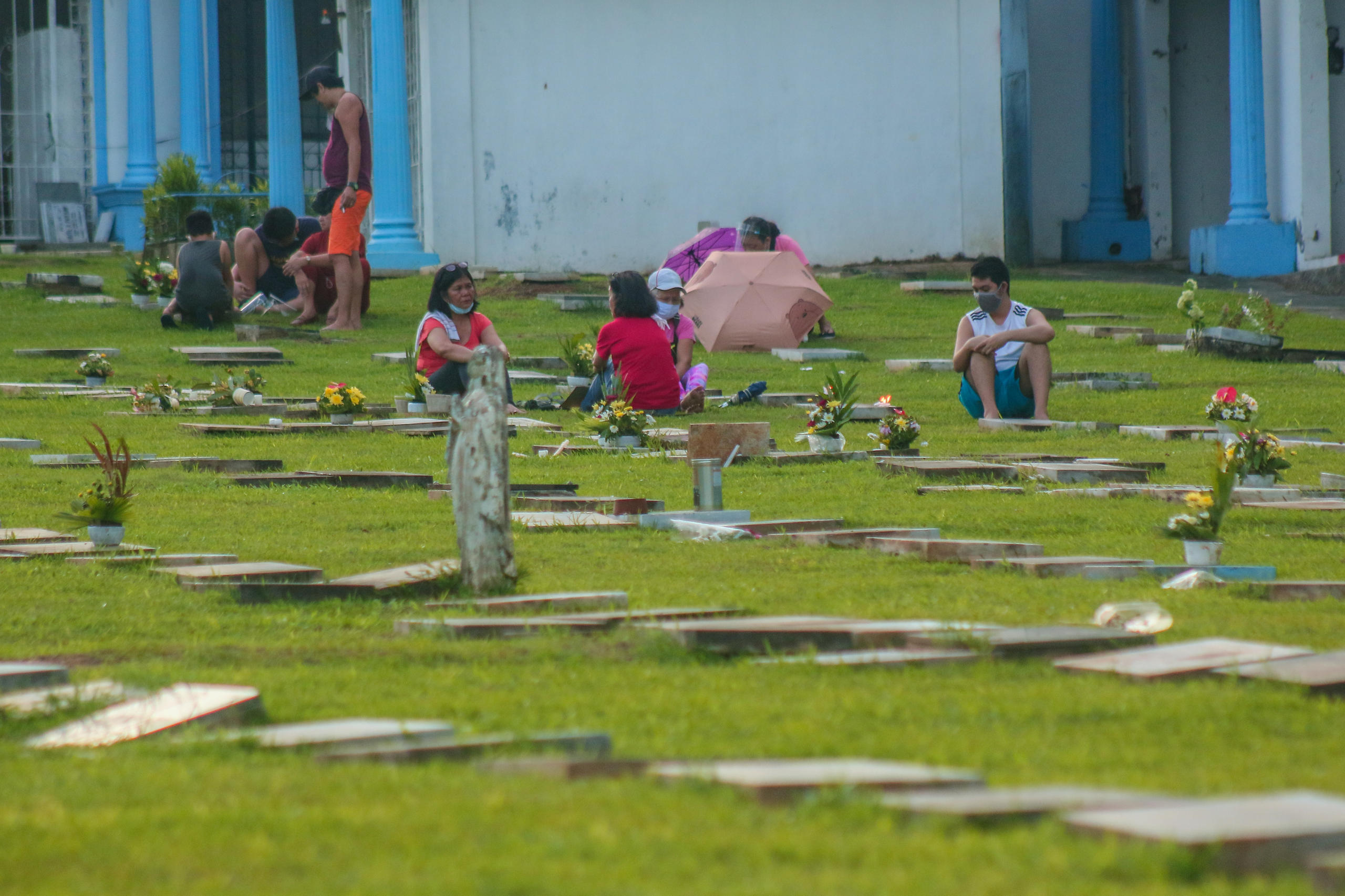 persone sedute tra le tombe di un cimitero