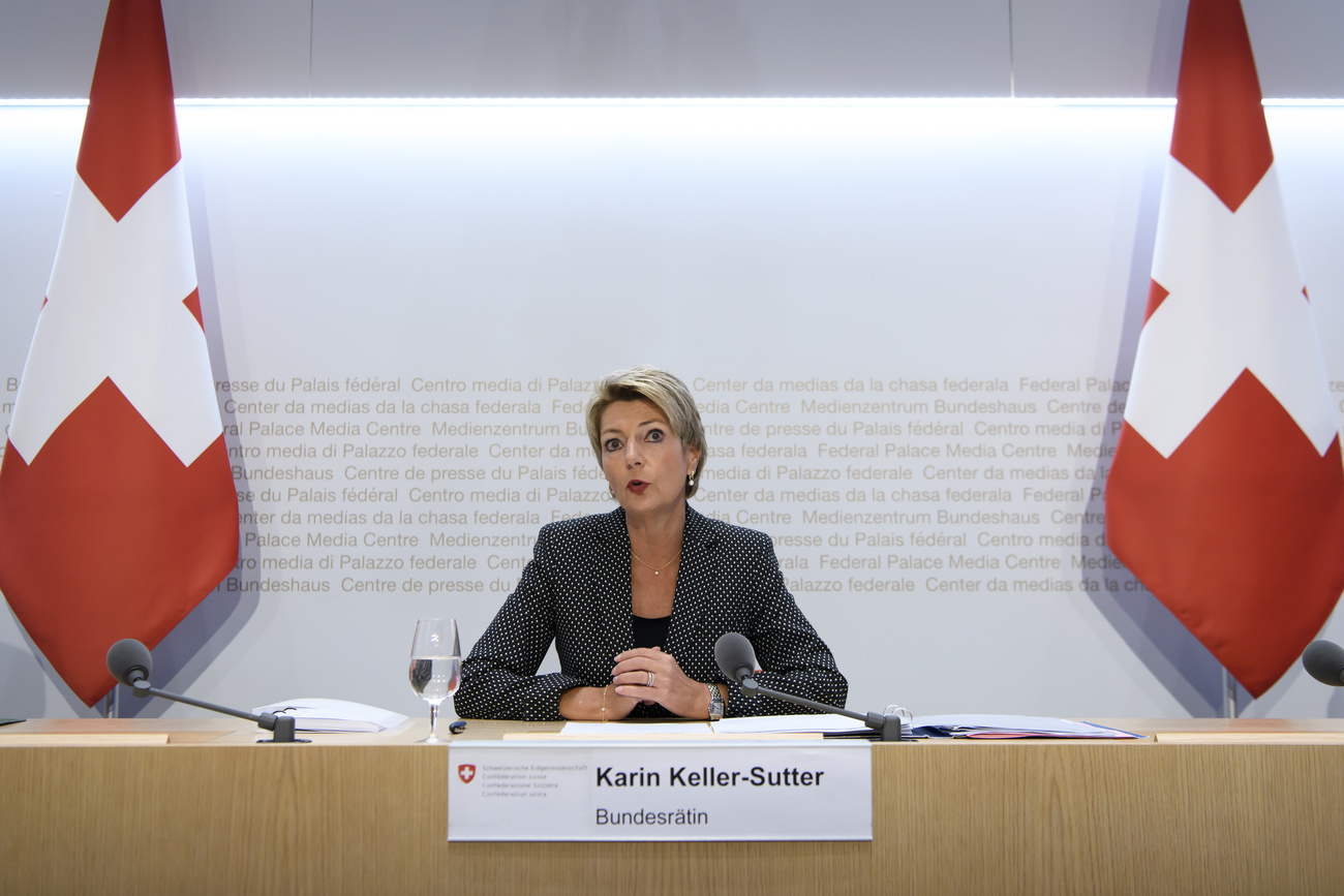 Bundesrätin Karin Keller-Sutter spricht zu den Medien, flankiert von zwei Schweizer Fahnen