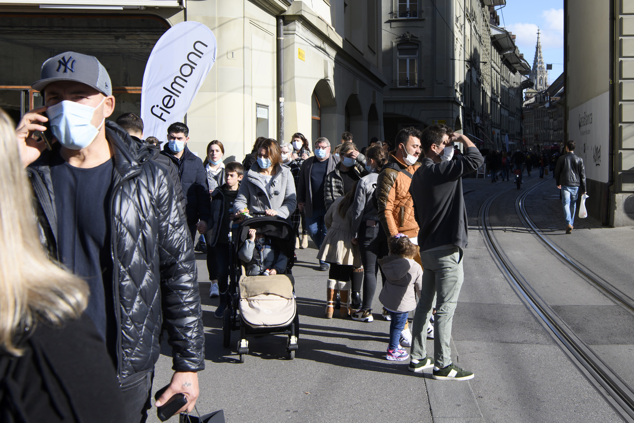 Persone con mascherine a una fermata del tram in centro a Berna