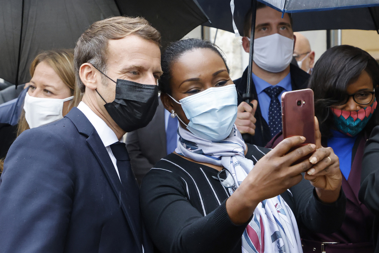 Macron che si presta a un selfie con una ragazza di colore a Les Mureaux.