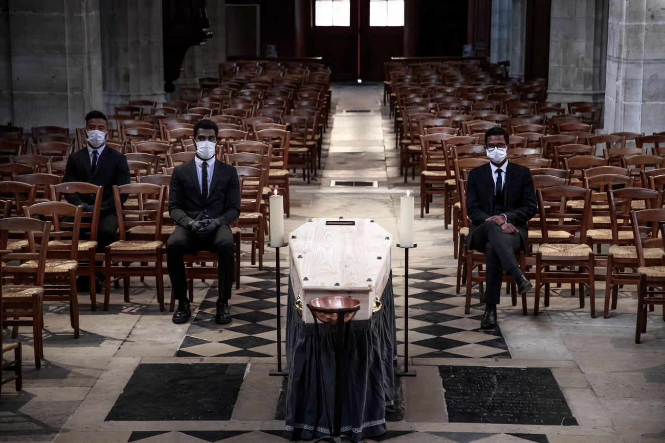 tre uomini con mascherina seduti su sedia di legno in una chiesa