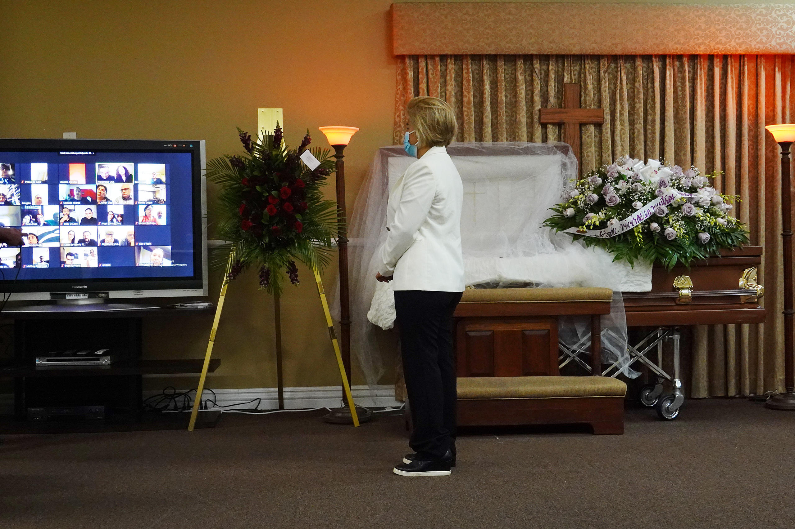 una donna con mascherina guarda uno schermo in una camera mortuaria