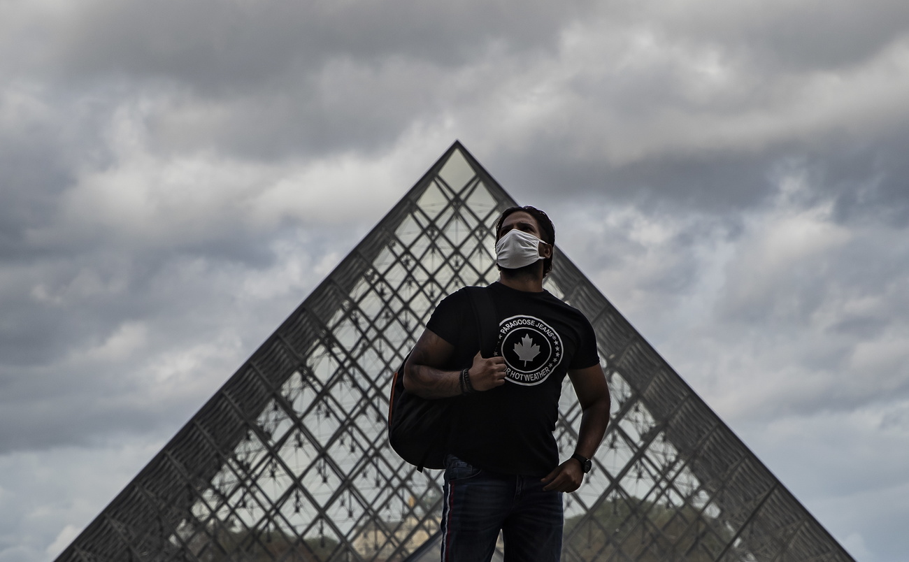 Un uomo con la mascherina davanti alla piramide del Louvre.