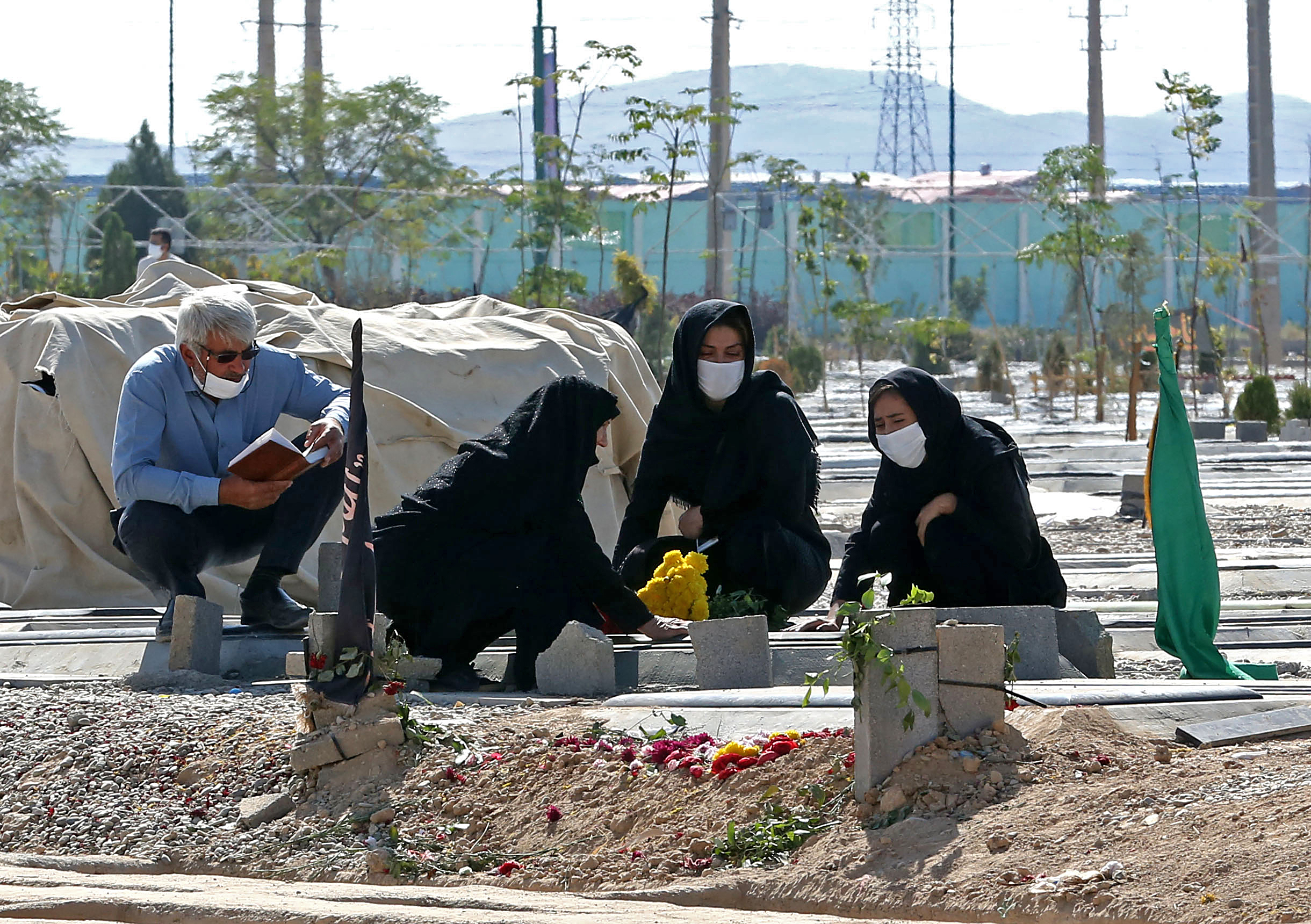 quattro persone con mascherina attorno a una tomba