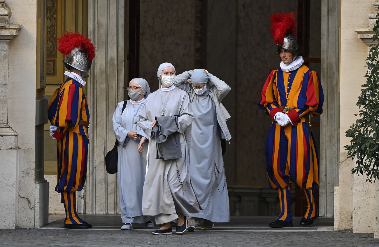 Des nonnes masquées passent à côté de deux gardes suisses au Vatican.
