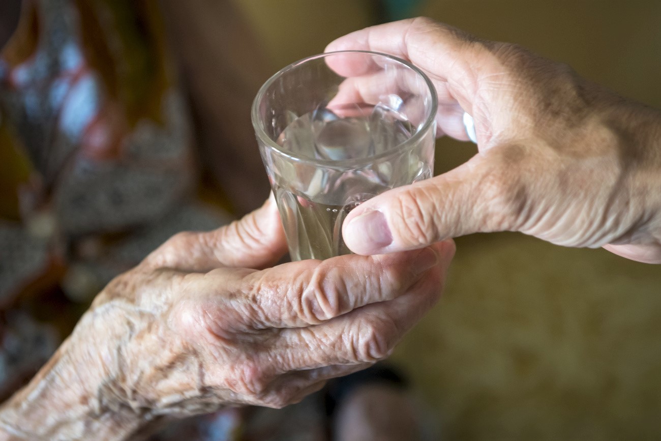 main d une personnes âgée tenant un verre d eau