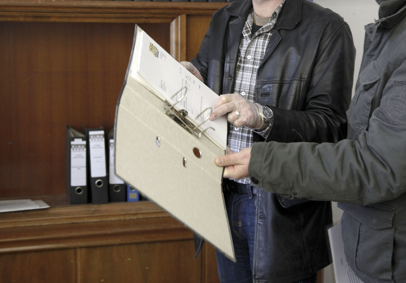 Two people check paperwork in a binder