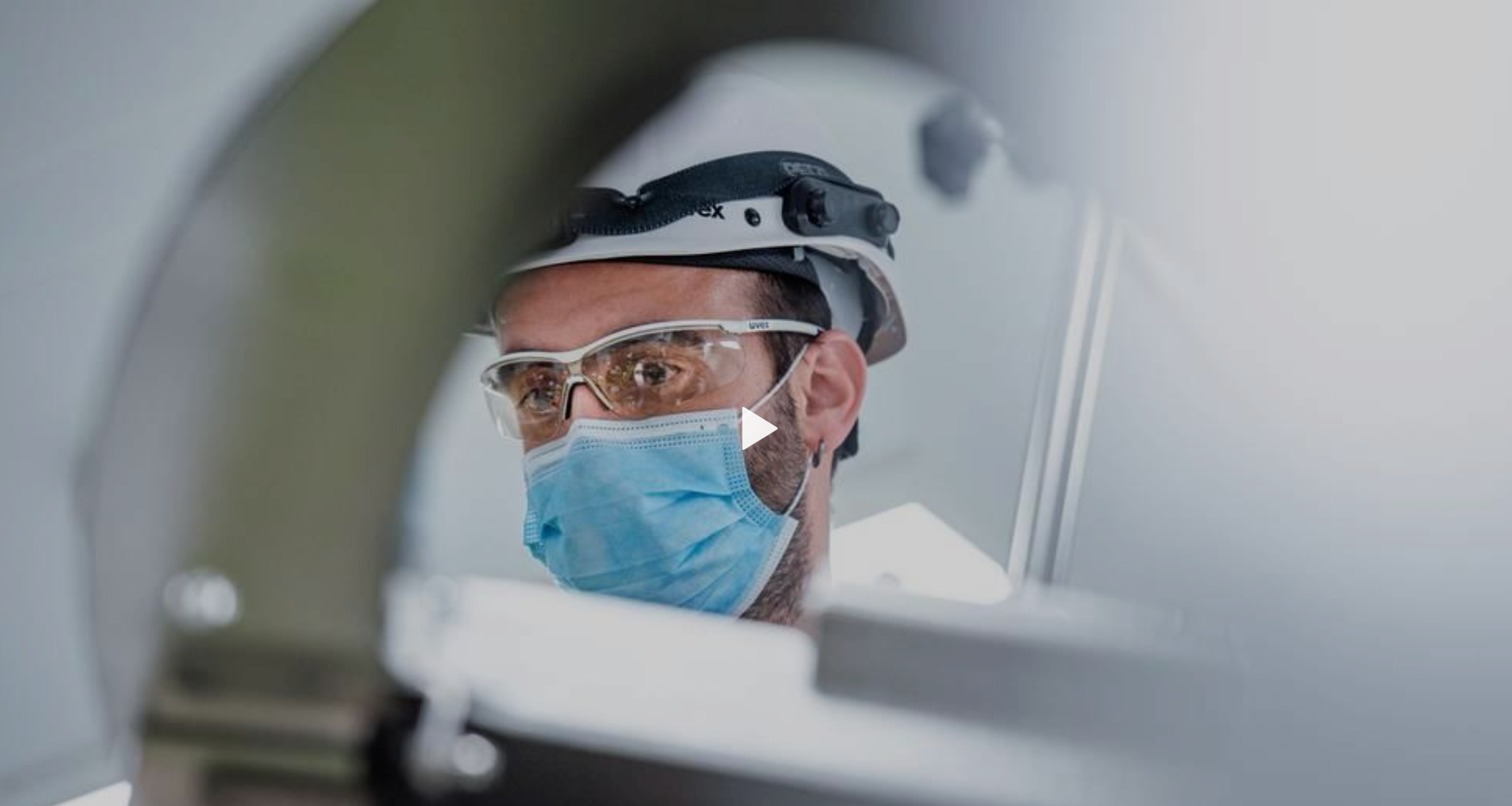 Professionista sanitario con mascherina, casco e occhiali di protezione intravisto attraverso apparecchiature mediche