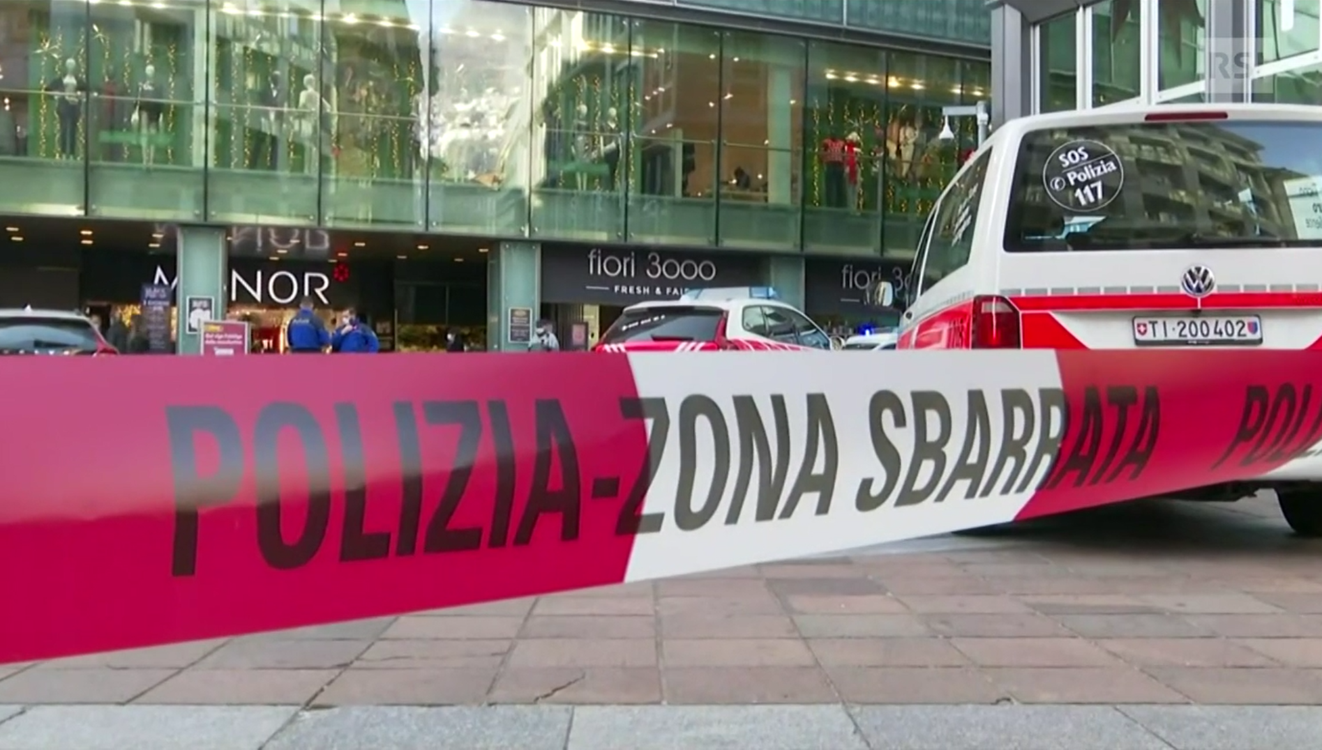 Primo piano di nastro rosso-bianco Polizia zona sbarrata ; si intravvede entrata grande magazzino