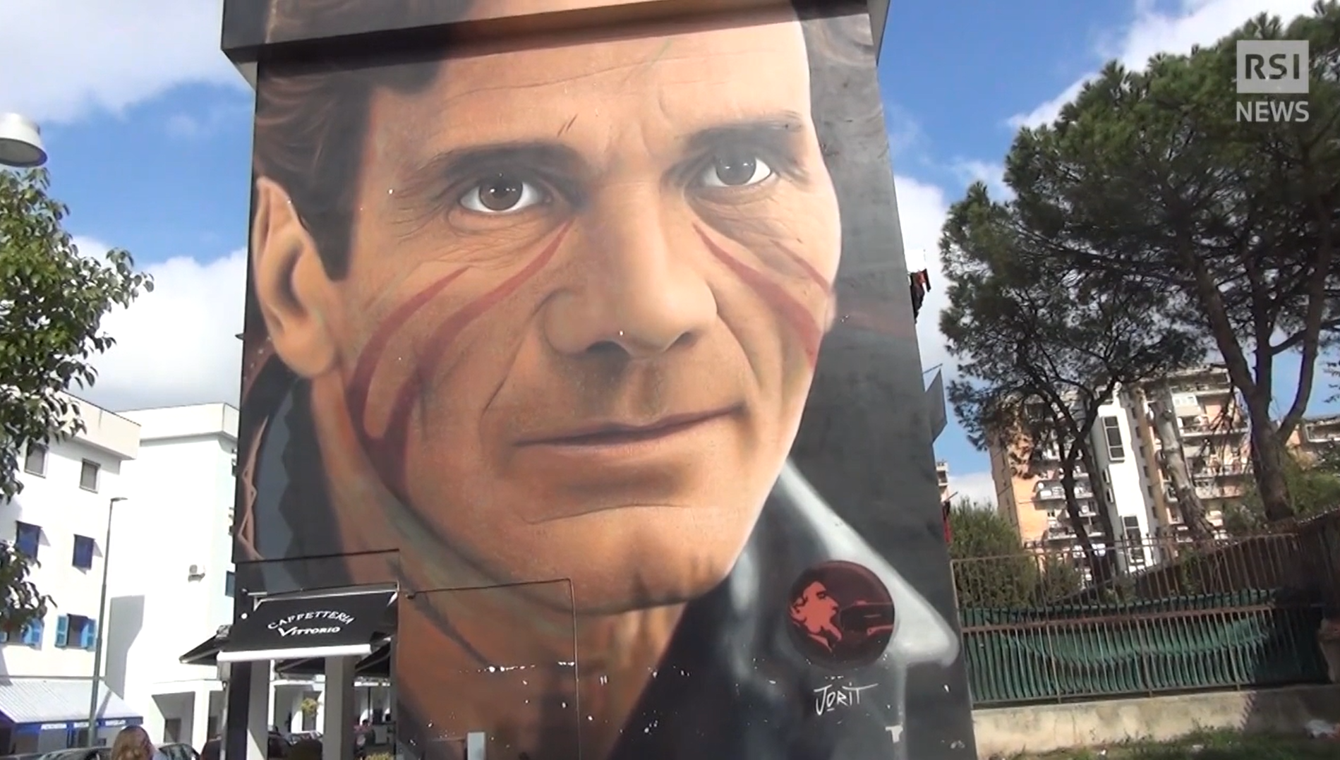 Palazzo popolare in cemento armato con dipinto a grosso murale il volto di un uomo con strisce rosse sulle guance