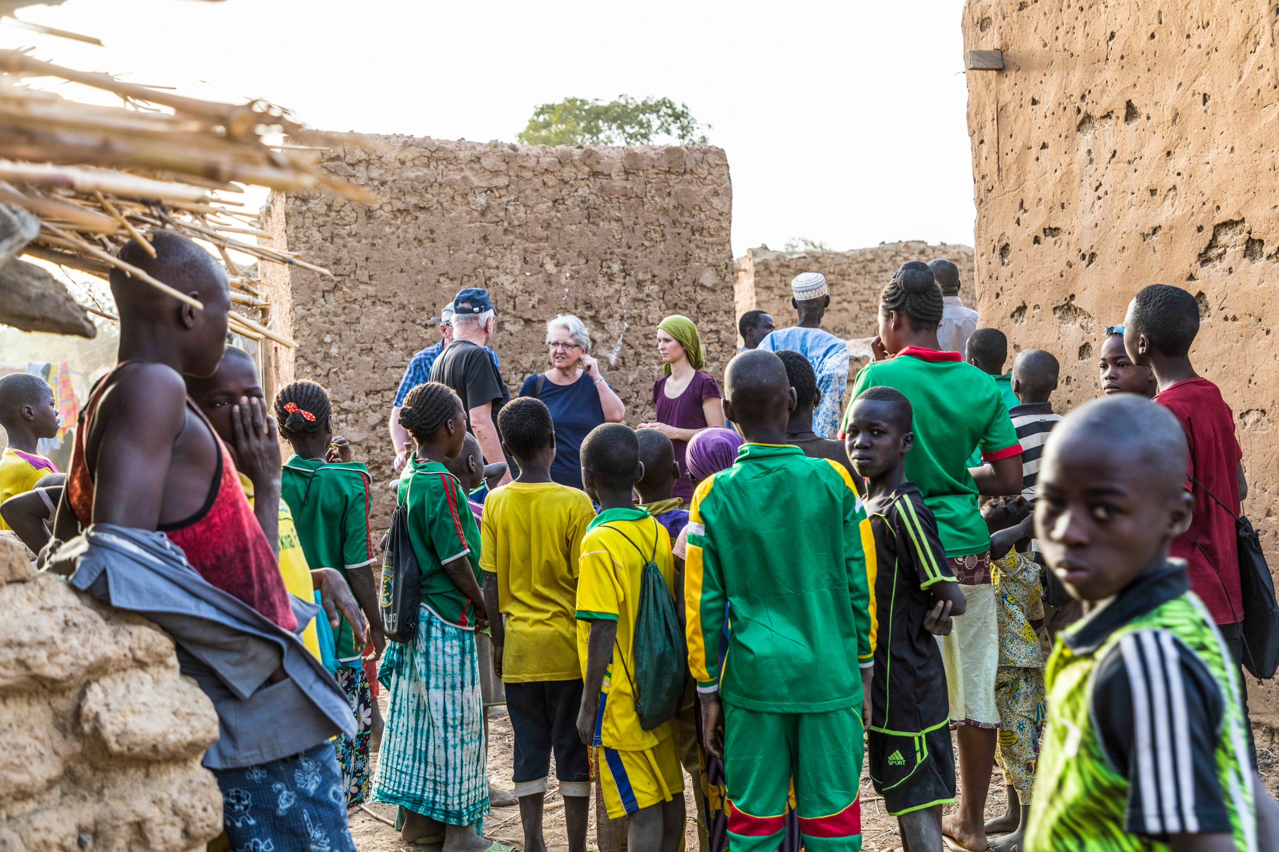 أطفال ونساء ورجال في قرية افريقية مع مجموعة من الأوروبيين