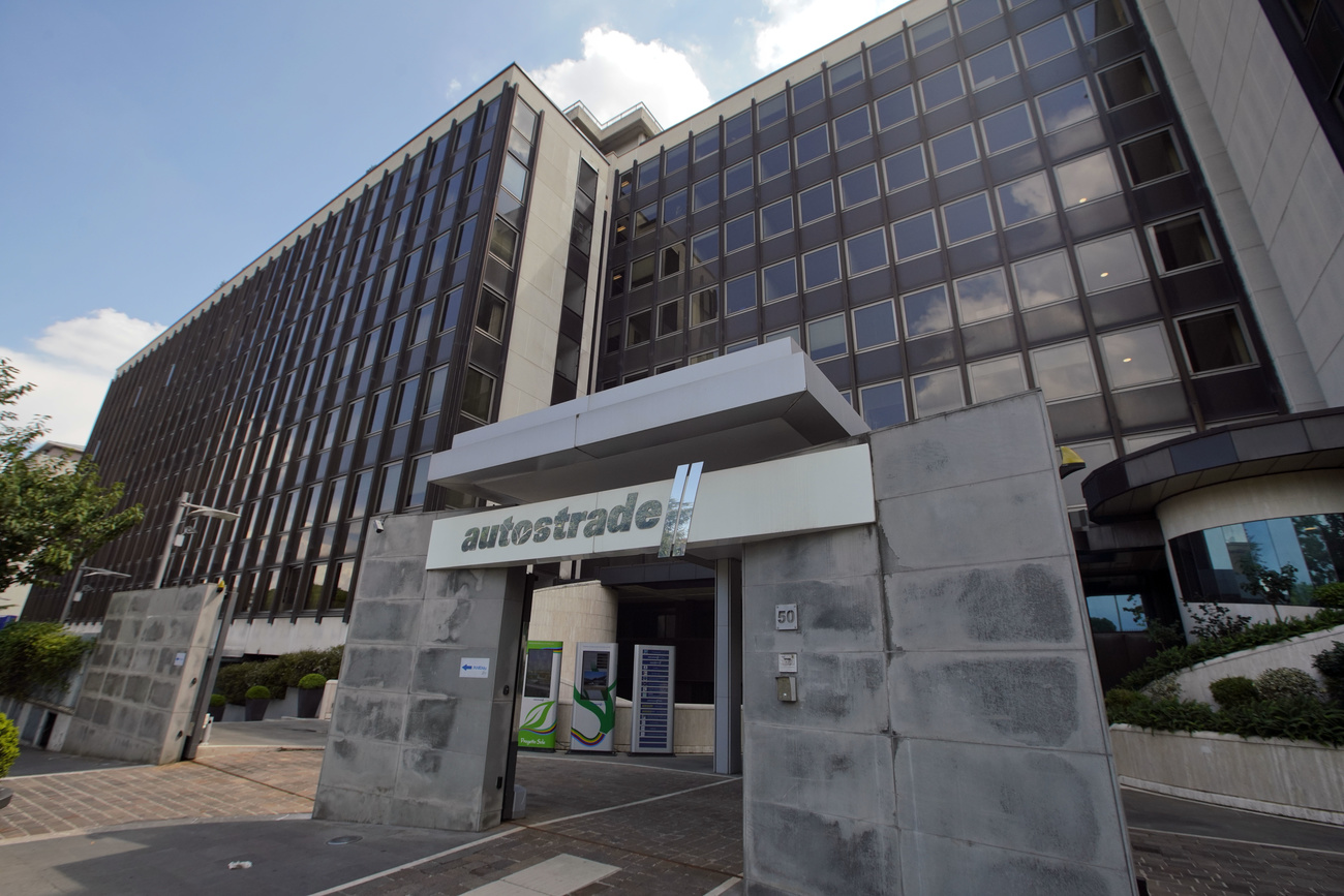 Vista dal basso in prospettiva di edificio con facciata a vetri e insegna Autostrade