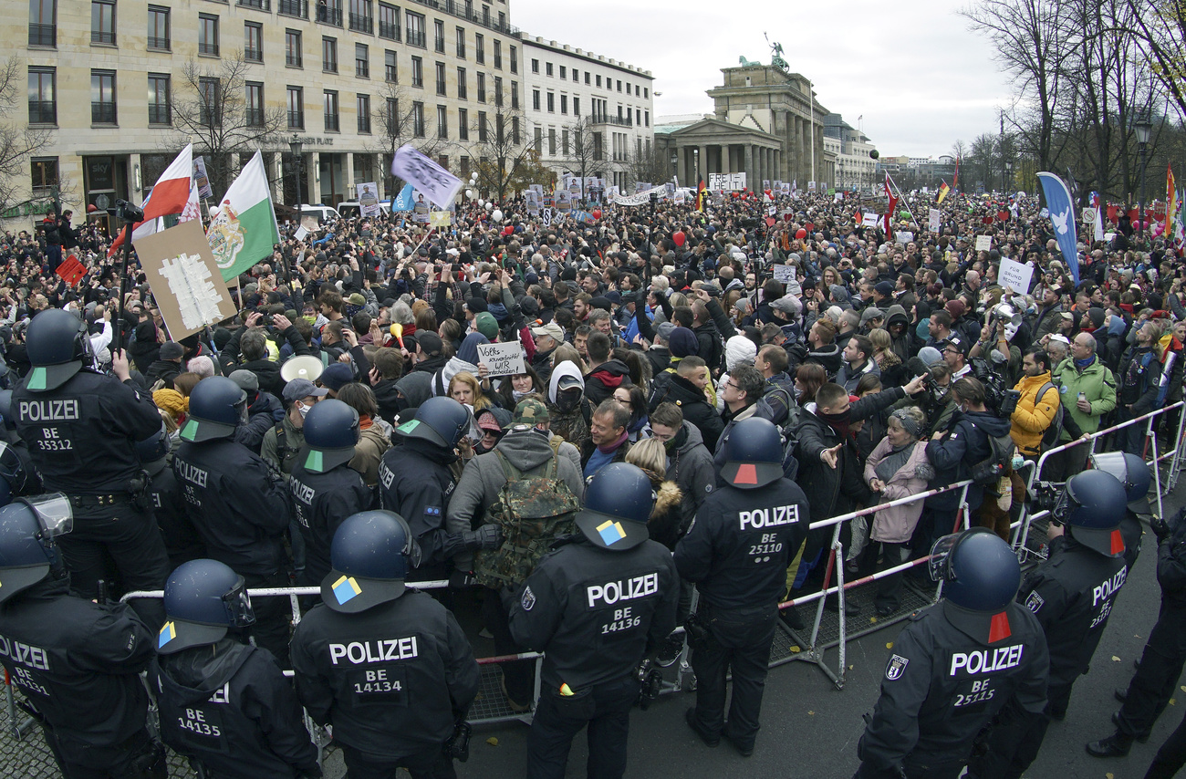 Migliaia di manifestanti a Berlino: i pochi con la maschera è per nascondere il volto.