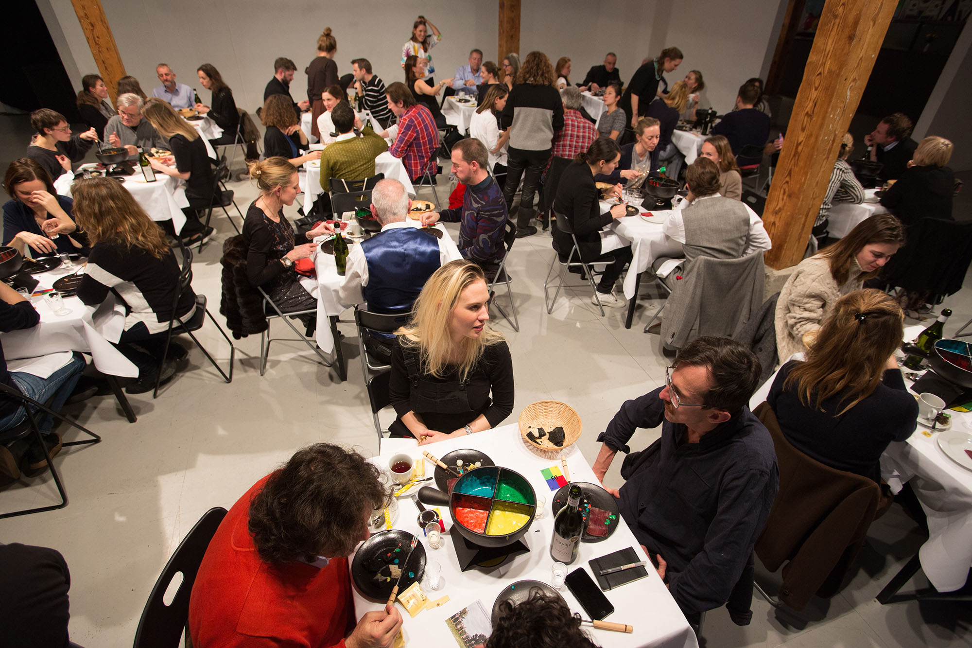 Personnes attablées autour de fondues multicolores.