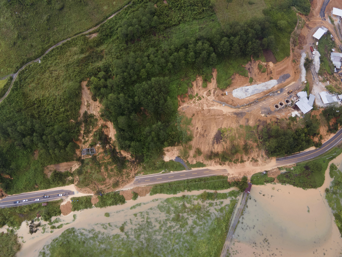 Veduta aerea di una zona collinare in cui due grosse frane hanno travolto una strada e un complesso industriale