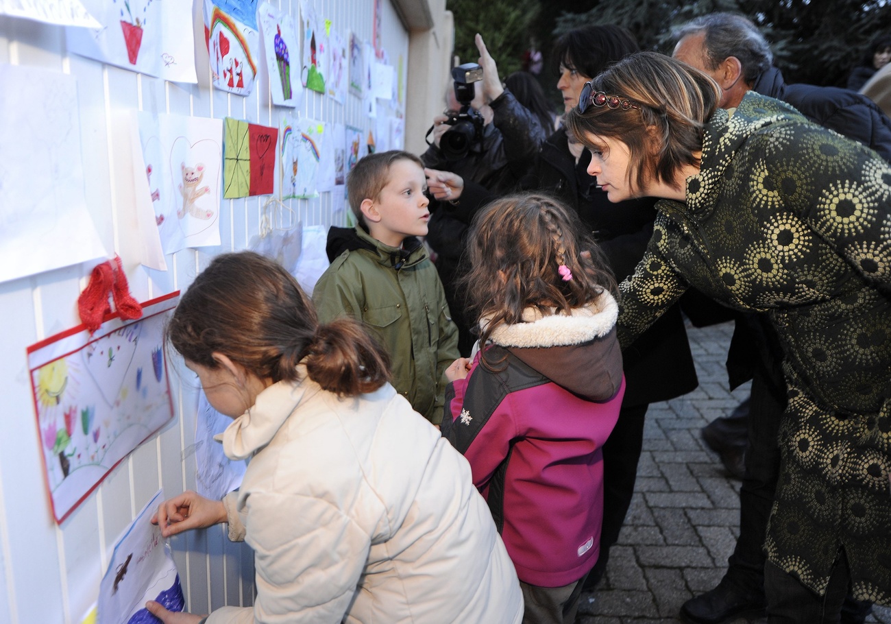 Bmbini che appendono i loro disegni a una parete per solidarietà della scomparsa di una loro amica.