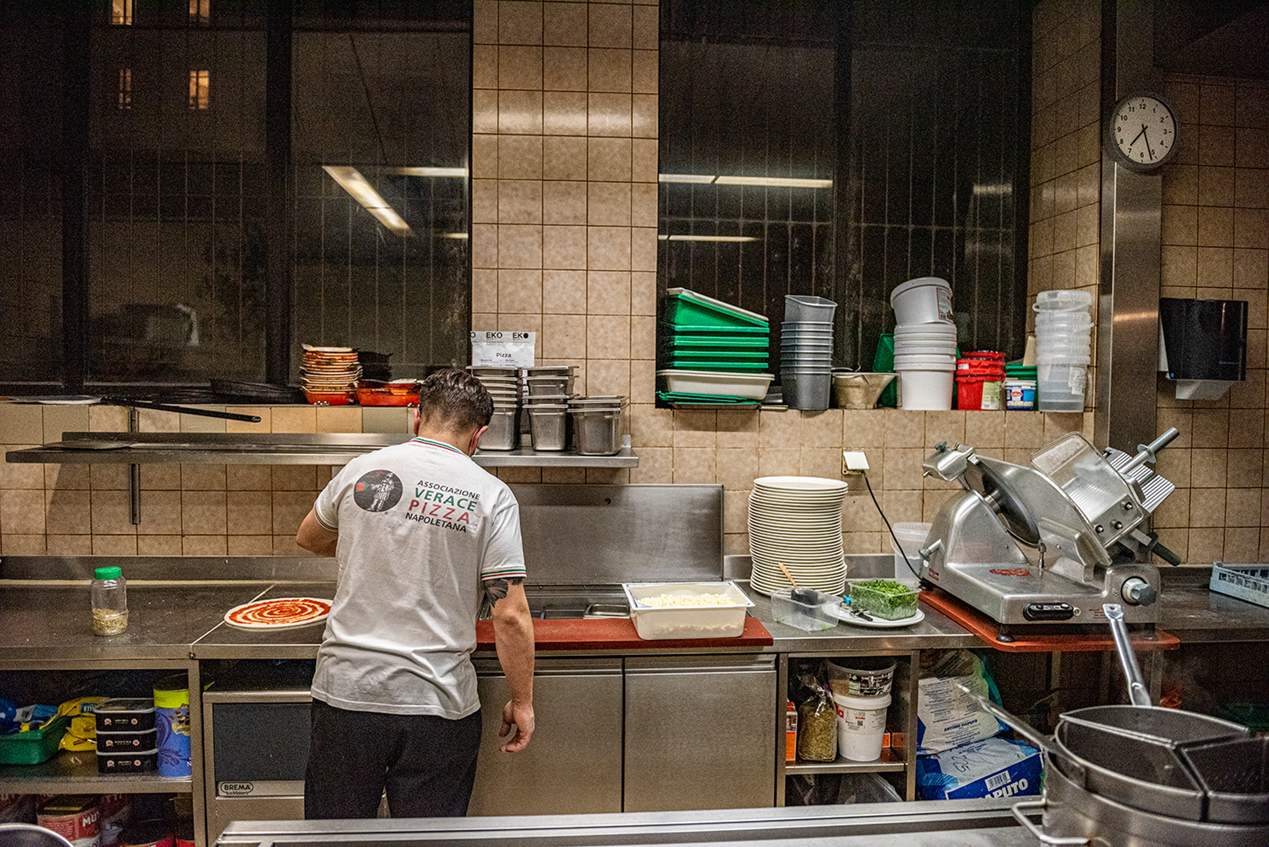 un uomo prepara una pizza in una cucina di un ristorante