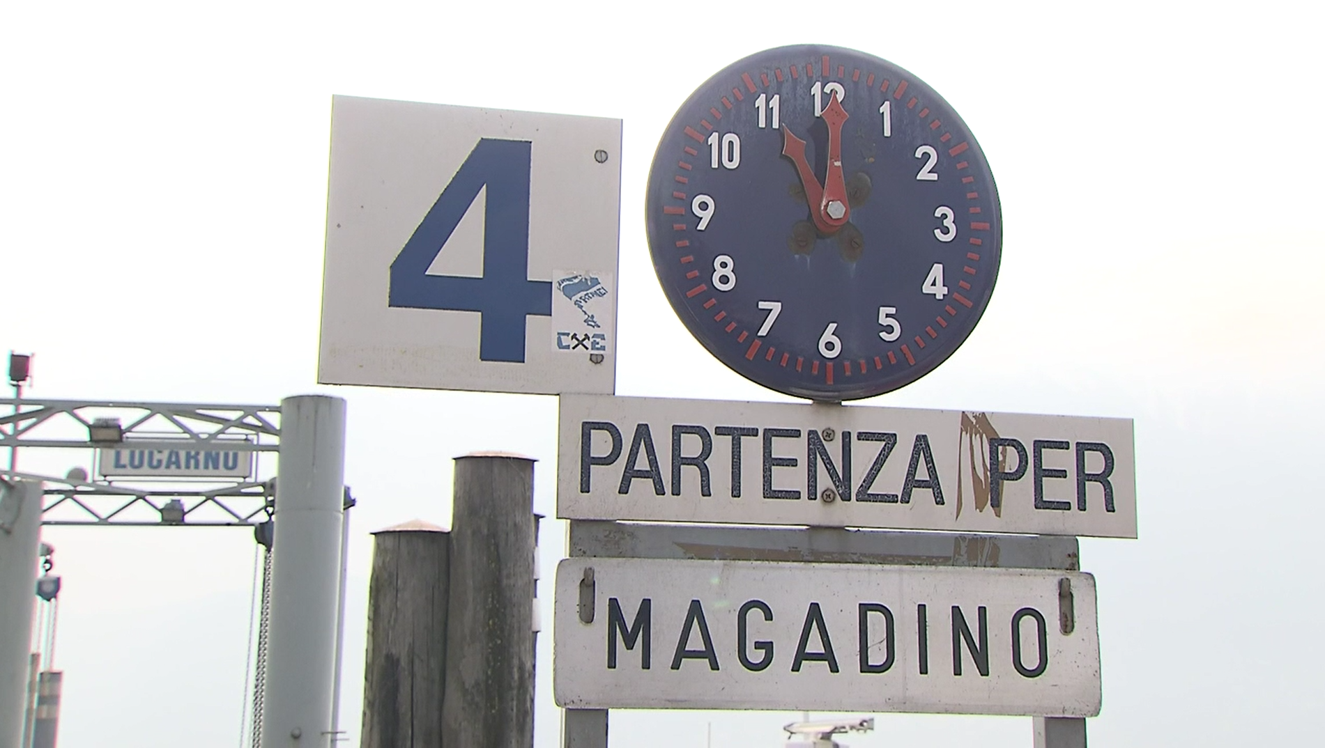 Visione parziale di un molo con cartello Locarno e insegna Partenza per Magadino