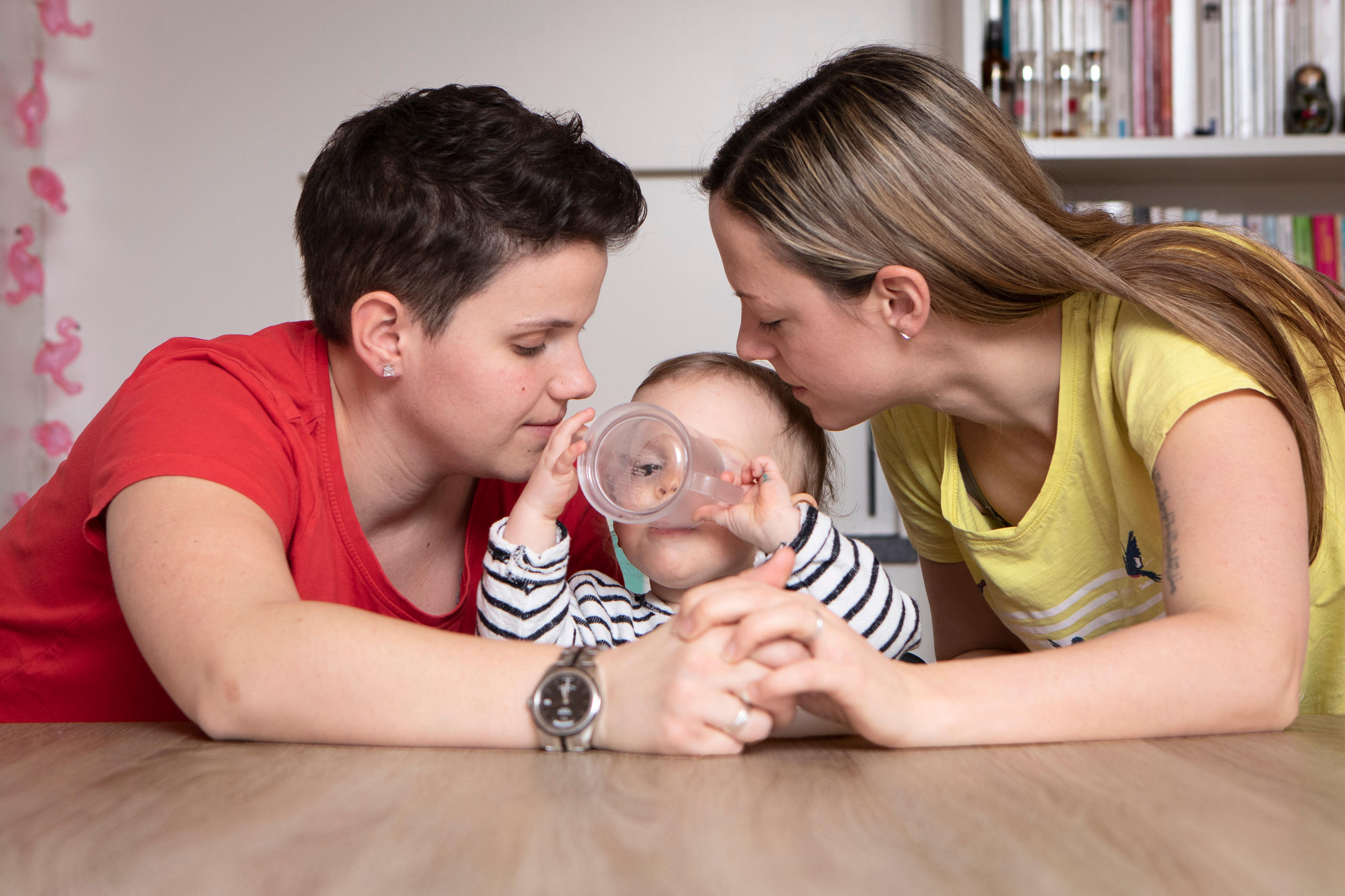 Un couple de femmes entoure leur enfant.