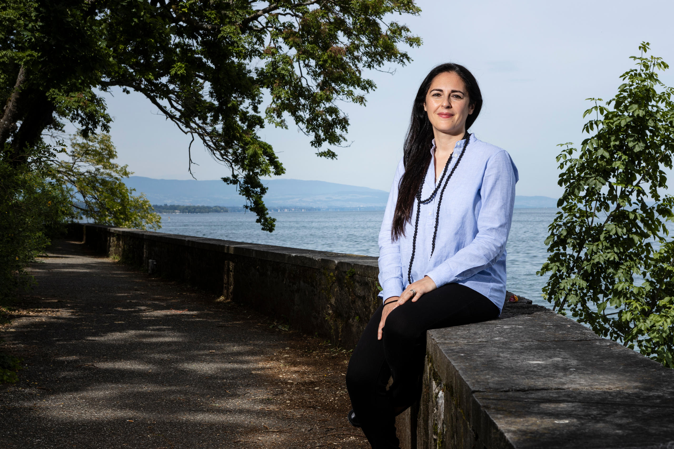 Femme assise sur un mur au bord d un lac