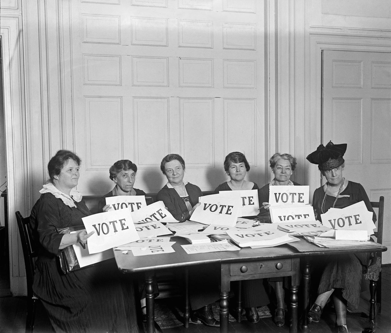 Femmes attablées brandissant des pancartes