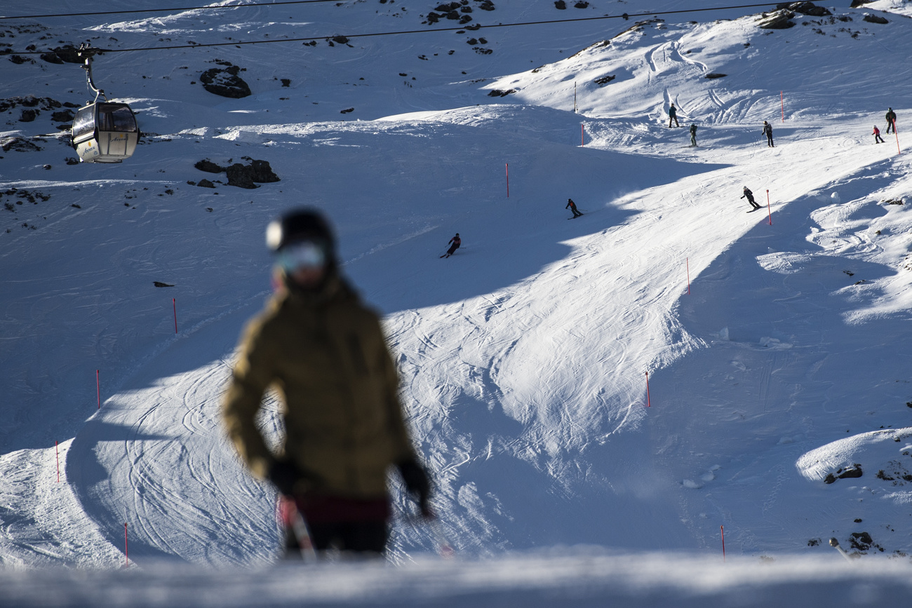 Pista da sci, sciatori, cabina di funivia in lontananza, sciatrice sfocata in primo piano