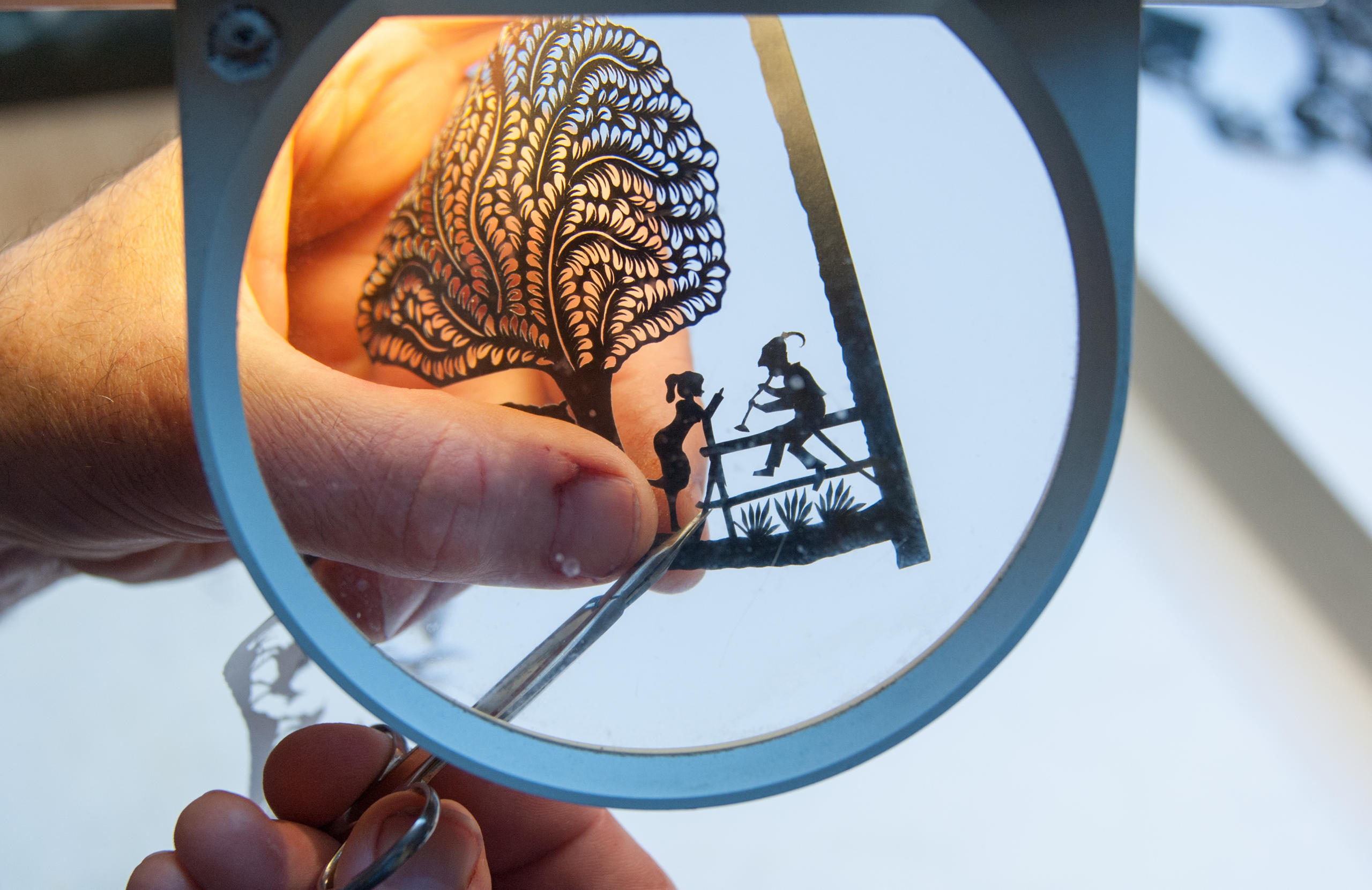 cutting paper under a magnifying glass
