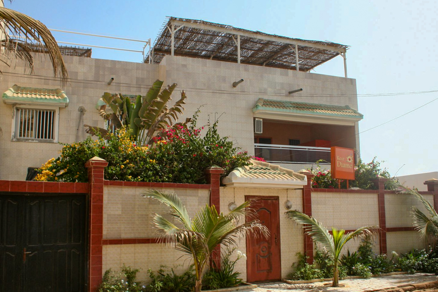 Façade d un bâtiment avec clôture et palmiers.