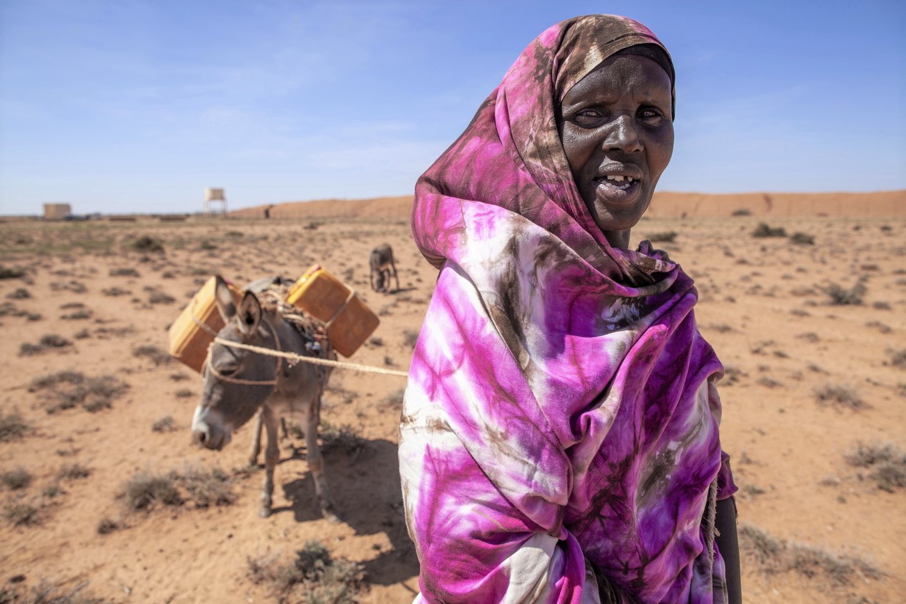 Mujer africana con un burro en una zona árida