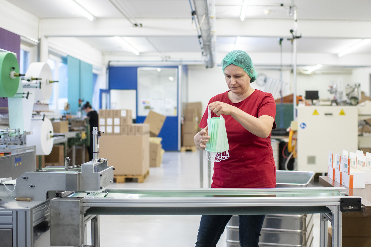 Empleados trabajando en la producción de mascarillas quirúrgicas en una fábrica