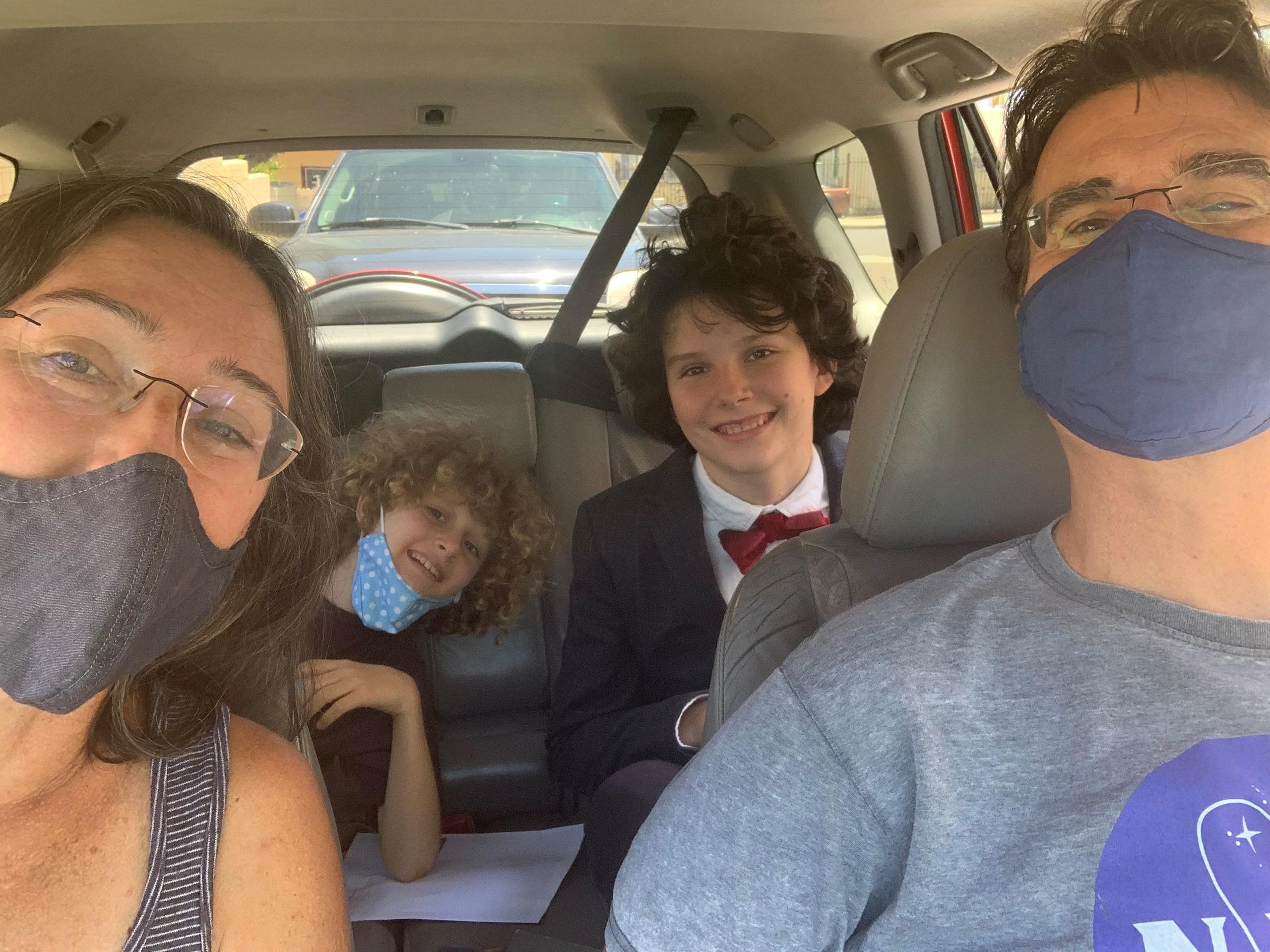 Familienbild: vier Personen im Auto mit Masken