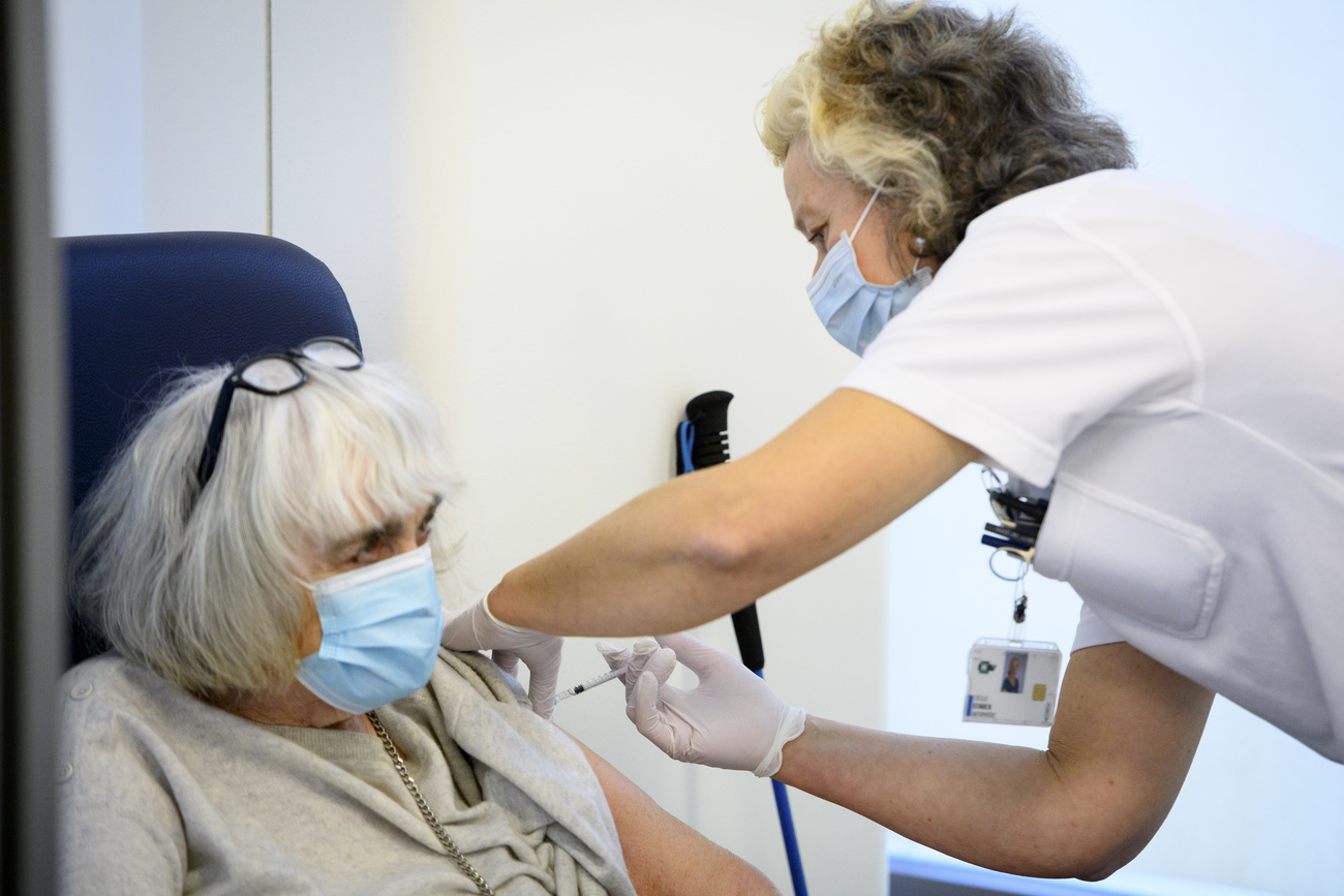 Una enfermera aplica una vacuna a una mujer mayor
