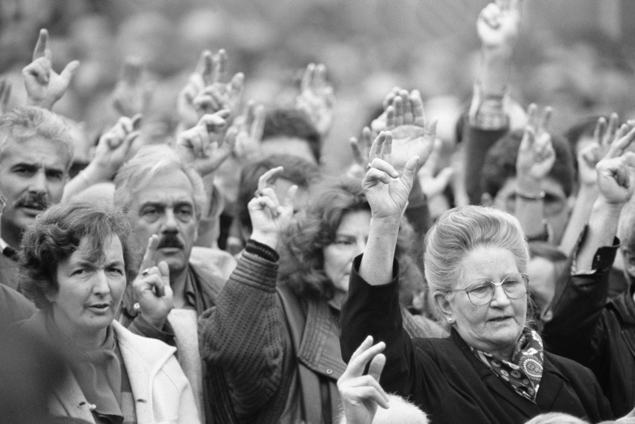 Foto en blanco y negro: hombres y mujeres votan a mano alzada
