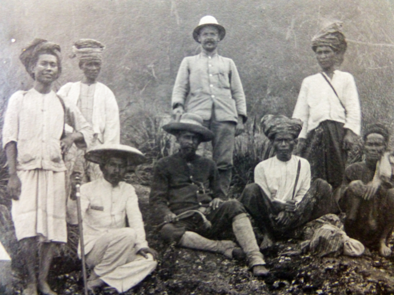 Scientifique avec un casque colonial entouré d indigènes malais