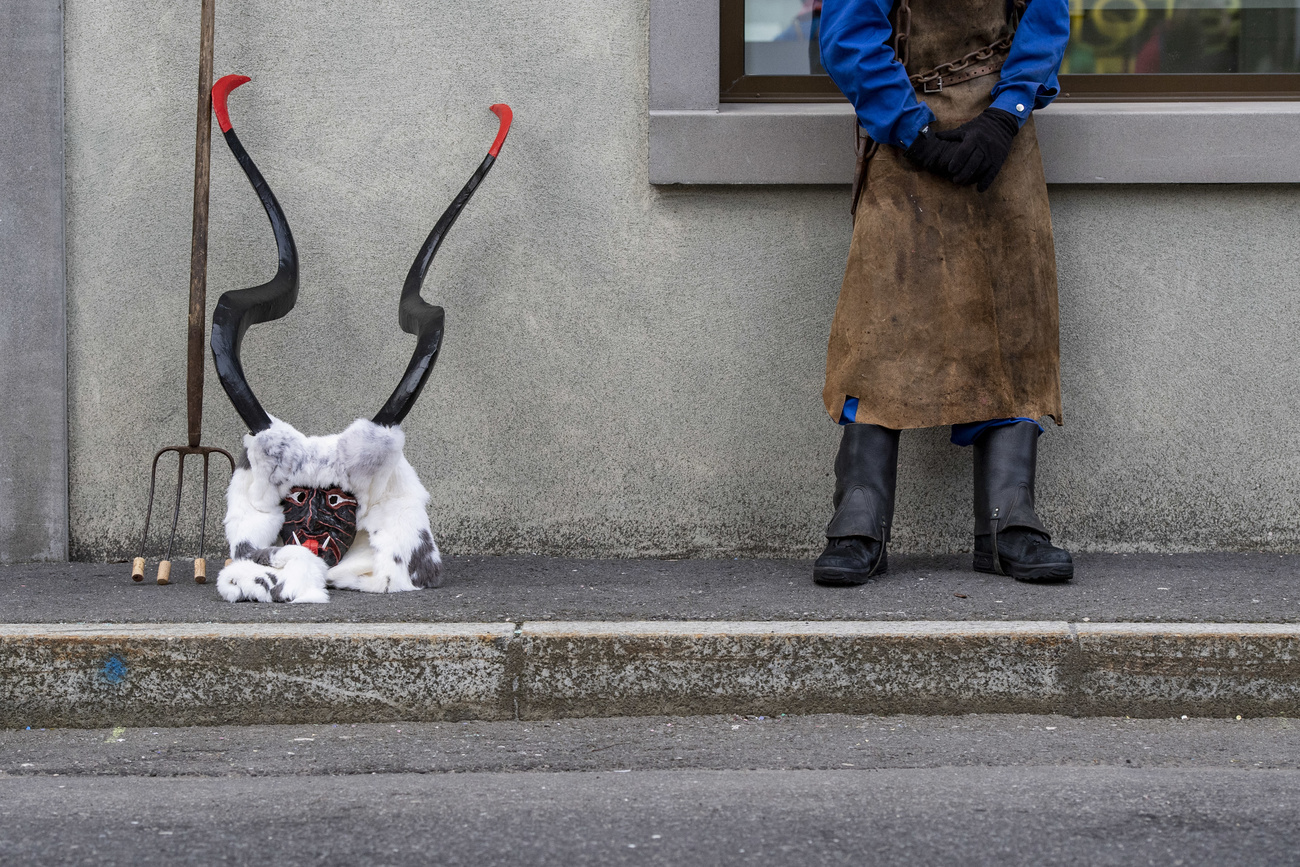 Maschera da diavolo e forca posate accanto al muro di una casa; si intravvede la persona in costume