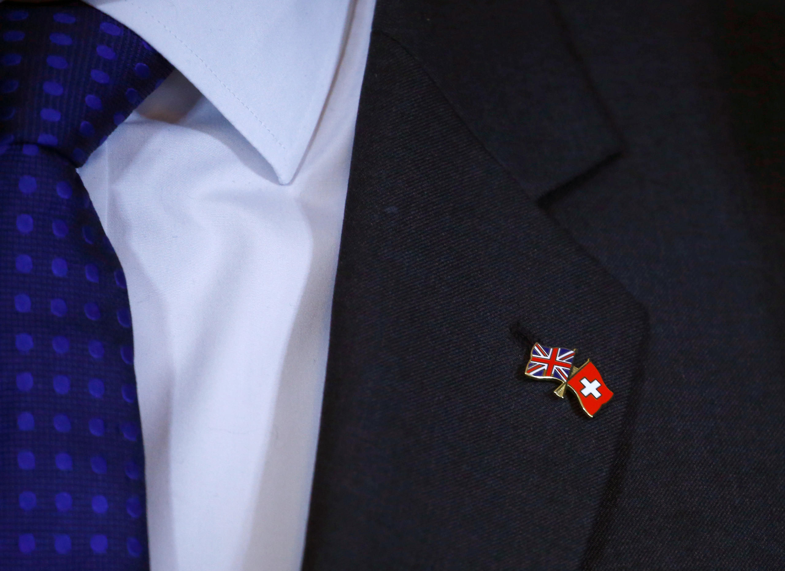 Un traje de hombe con alfiler de corbata con las banderas de Suiza y Reino Unido