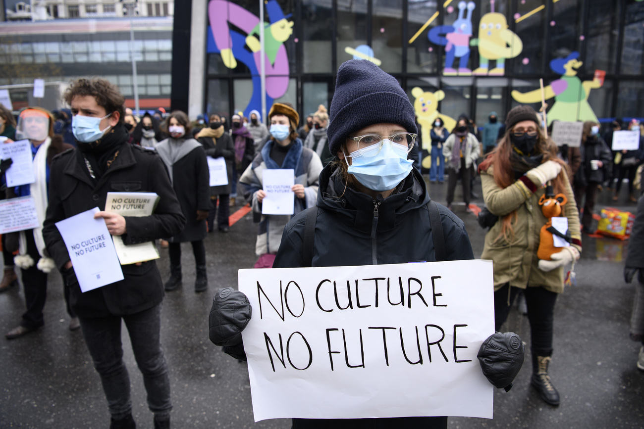 Gruppo di manifestanti distanziati e con mascherina; la ragazza in primo piano regge cartello No culture, no future