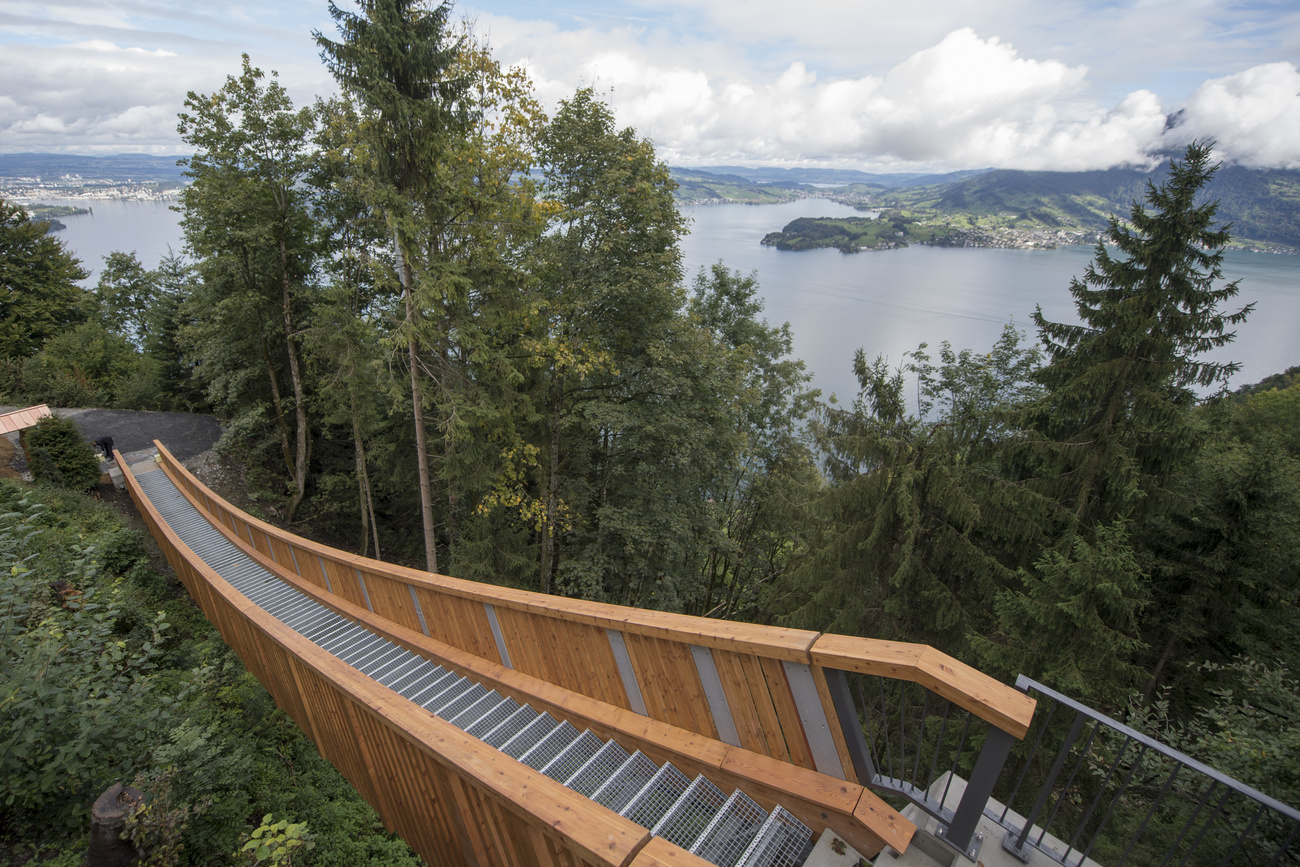 Passerella di legno in area boschiva dalla quale si ha vista aperta su ampia regione lacustre prealpina